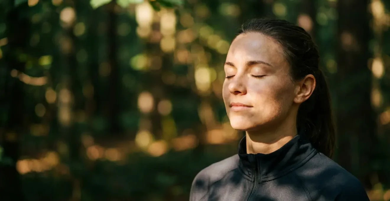 Athlete with eyes closed listening attentively to forest sounds in serene woodland setting