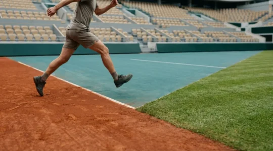 Professional tennis player transitioning between different court surfaces showcasing knee biomechanics