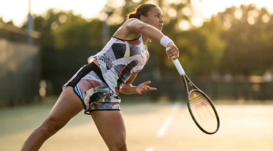 Tennis player at peak serve motion showcasing racket dynamics and energy transfer