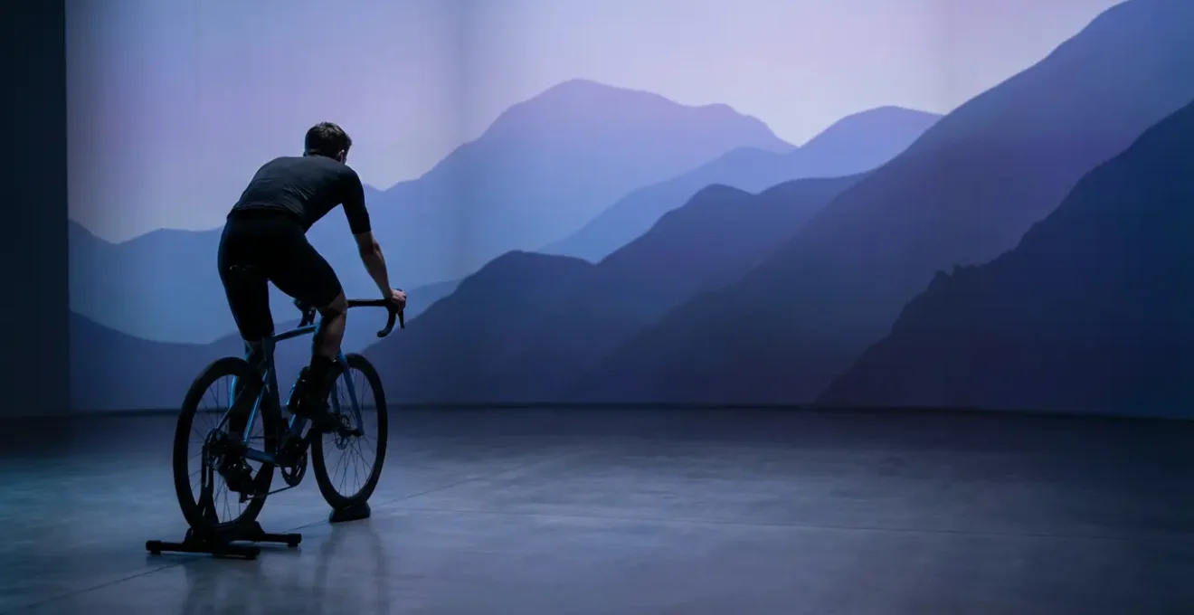 Cyclist in immersive virtual reality training environment with dramatic landscape projections