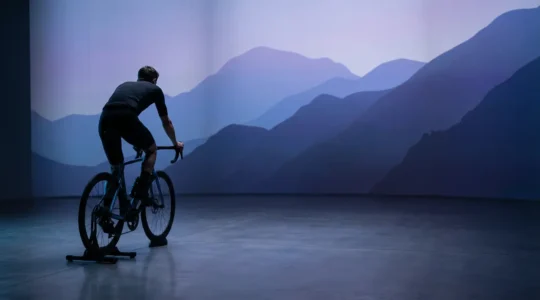 Cyclist in immersive virtual reality training environment with dramatic landscape projections